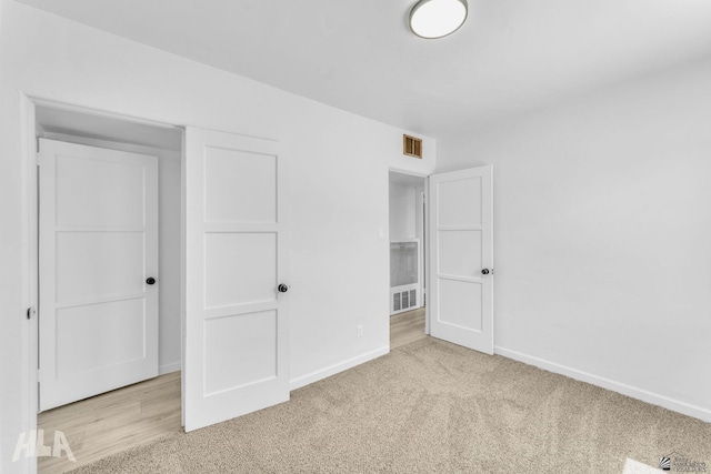 unfurnished bedroom with light colored carpet, baseboards, and visible vents
