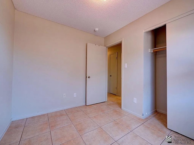 8576 E 38th St, Yuma, AZ 85365 - unfurnished bedroom featuring a textured ceiling, light tile patterned floors, and a closet
