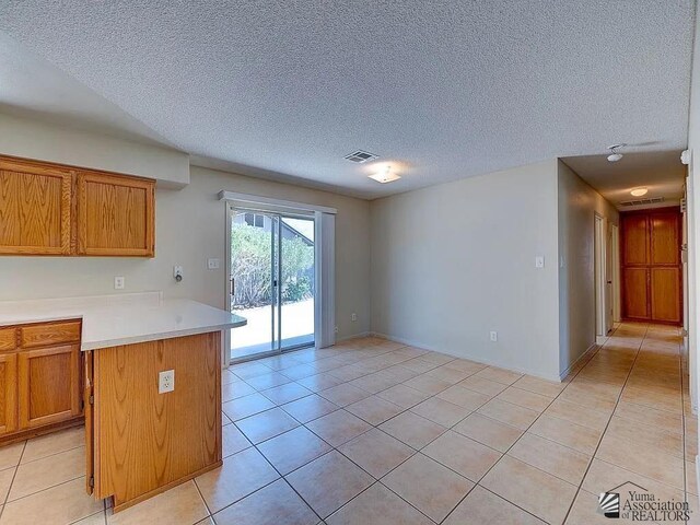 8576 E 38th St, Yuma, AZ 85365 - kitchen with light tile patterned flooring, light countertops, brown cabinetry, and a textured ceiling