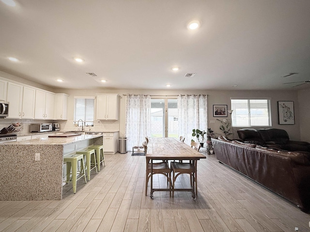 14650 E 42nd Pl, Yuma, AZ 85367 - kitchen featuring appliances with stainless steel finishes, light wood-type flooring, a breakfast bar, light stone countertops, and white cabinetry