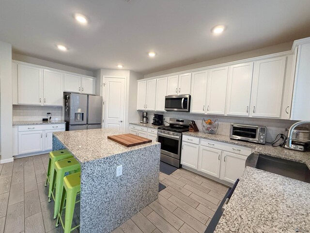 14650 E 42nd Pl, Yuma, AZ 85367 - kitchen featuring stainless steel appliances, a center island, backsplash, light wood-style flooring, and white cabinetry