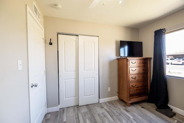 bedroom featuring a closet, light wood-style floors, baseboards, and a ceiling fan