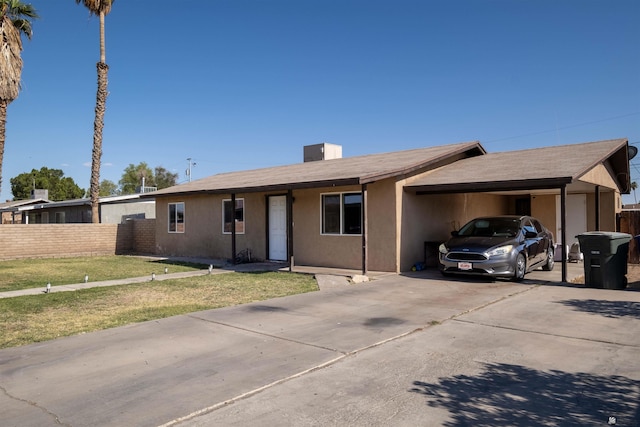 ranch-style house with driveway, an attached carport, and a chimney