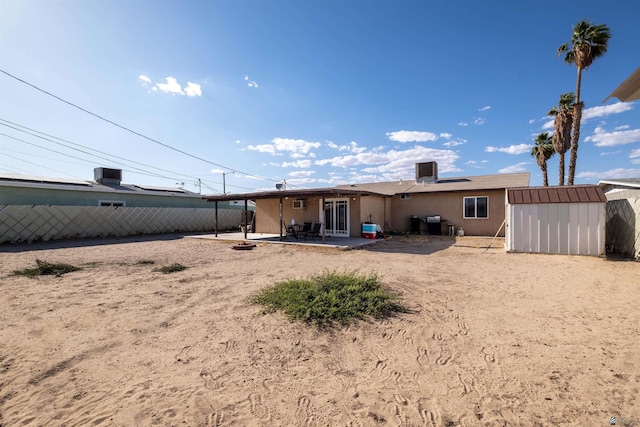rear view of house with a patio, a shed, an outbuilding, and fence