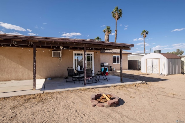 back of property with an outdoor fire pit, stucco siding, a shed, a patio area, and an outbuilding