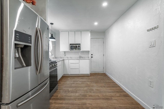 3566 W 5th St, Yuma, AZ 85364 - kitchen with appliances with stainless steel finishes, white cabinetry, light countertops, wood finished floors, and decorative backsplash