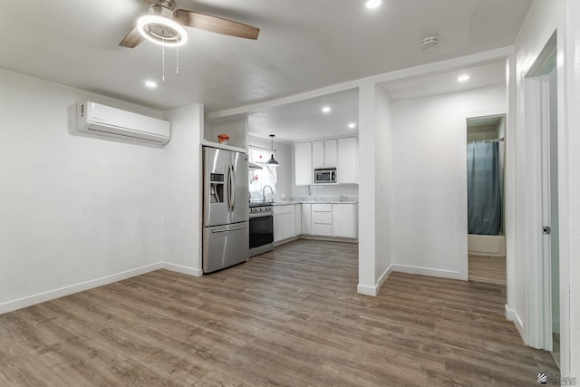 3566 W 5th St, Yuma, AZ 85364 - kitchen with stainless steel appliances, a wall unit AC, white cabinetry, baseboards, and a ceiling fan