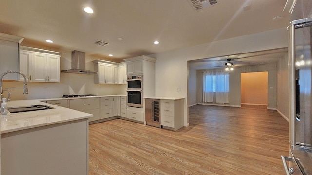 1350 S 6th Ave, Yuma, AZ 85364 - kitchen with wall chimney range hood, beverage cooler, appliances with stainless steel finishes, light wood-style floors, and a ceiling fan