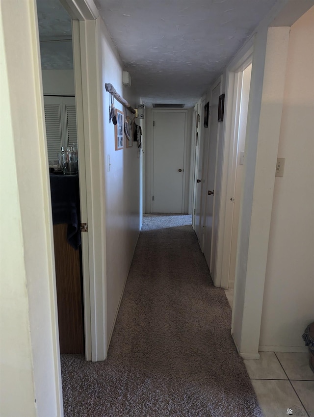 corridor featuring a textured ceiling and light tile patterned floors