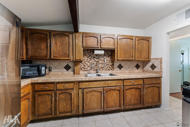 3186 S Elm St, Yuma, AZ 85364 - kitchen featuring black microwave, decorative backsplash, freestanding refrigerator, brown cabinets, and light tile patterned floors