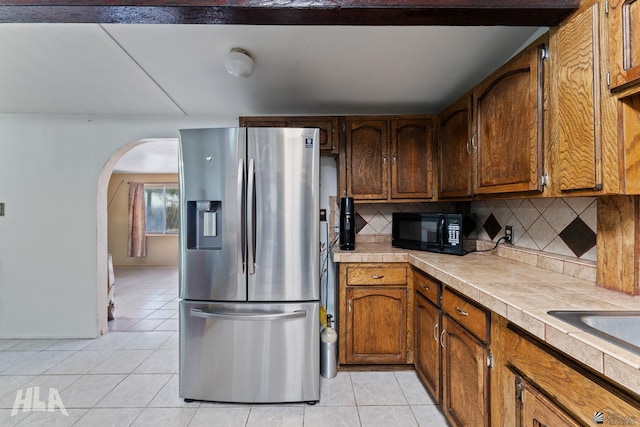 3186 S Elm St, Yuma, AZ 85364 - kitchen with stainless steel fridge, black microwave, light tile patterned floors, and arched walkways