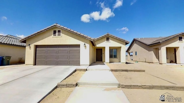 mediterranean / spanish home featuring concrete driveway, an attached garage, a tile roof, and stucco siding