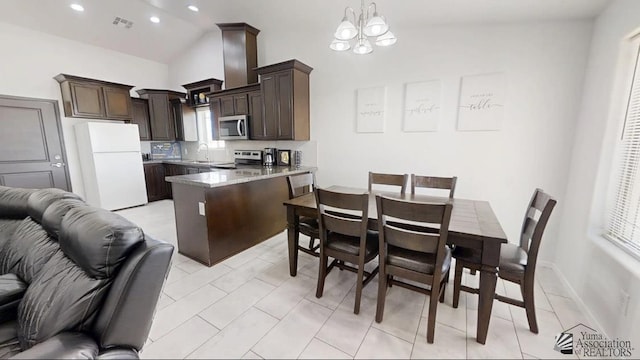 kitchen featuring dark brown cabinetry, appliances with stainless steel finishes, a peninsula, open floor plan, and visible vents