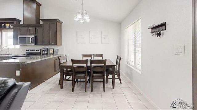 dining space with a healthy amount of sunlight, light tile patterned floors, vaulted ceiling, and a notable chandelier