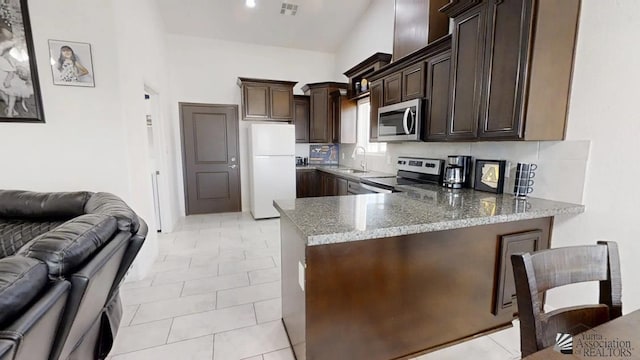 kitchen with visible vents, appliances with stainless steel finishes, light stone countertops, a peninsula, and open floor plan