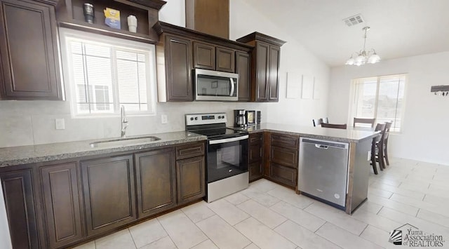 kitchen with appliances with stainless steel finishes, an inviting chandelier, a sink, plenty of natural light, and vaulted ceiling