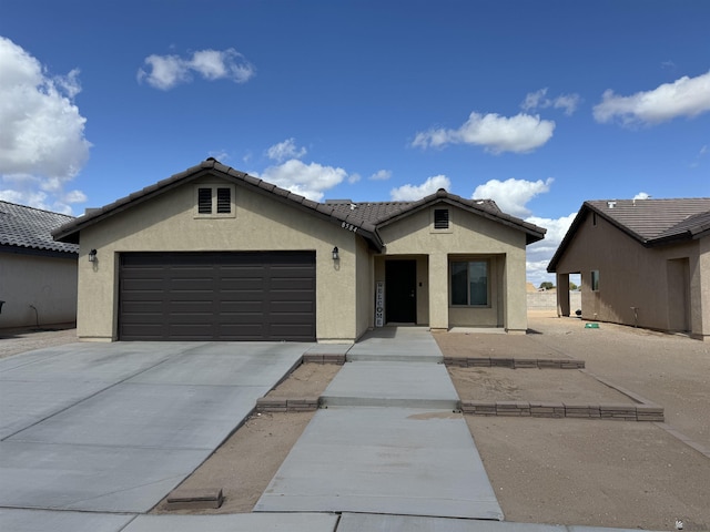 ranch-style house with a garage, stucco siding, a tile roof, and concrete driveway