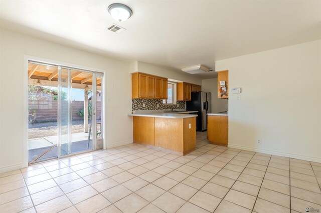 1986 S 47th Ave, Yuma, AZ 85364 - kitchen featuring black refrigerator with ice dispenser, a peninsula, light countertops, tasteful backsplash, and brown cabinetry