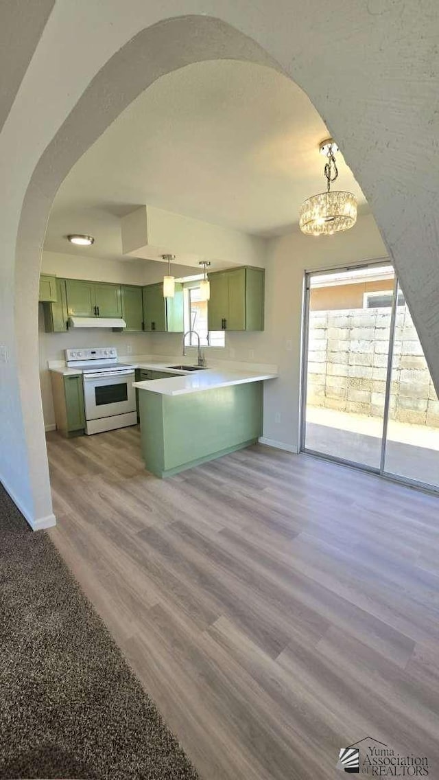kitchen with electric range, a peninsula, baseboards, green cabinetry, and a notable chandelier