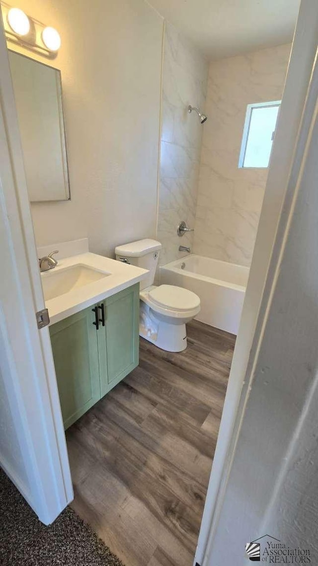 full bath featuring toilet, shower / washtub combination, wood finished floors, and vanity