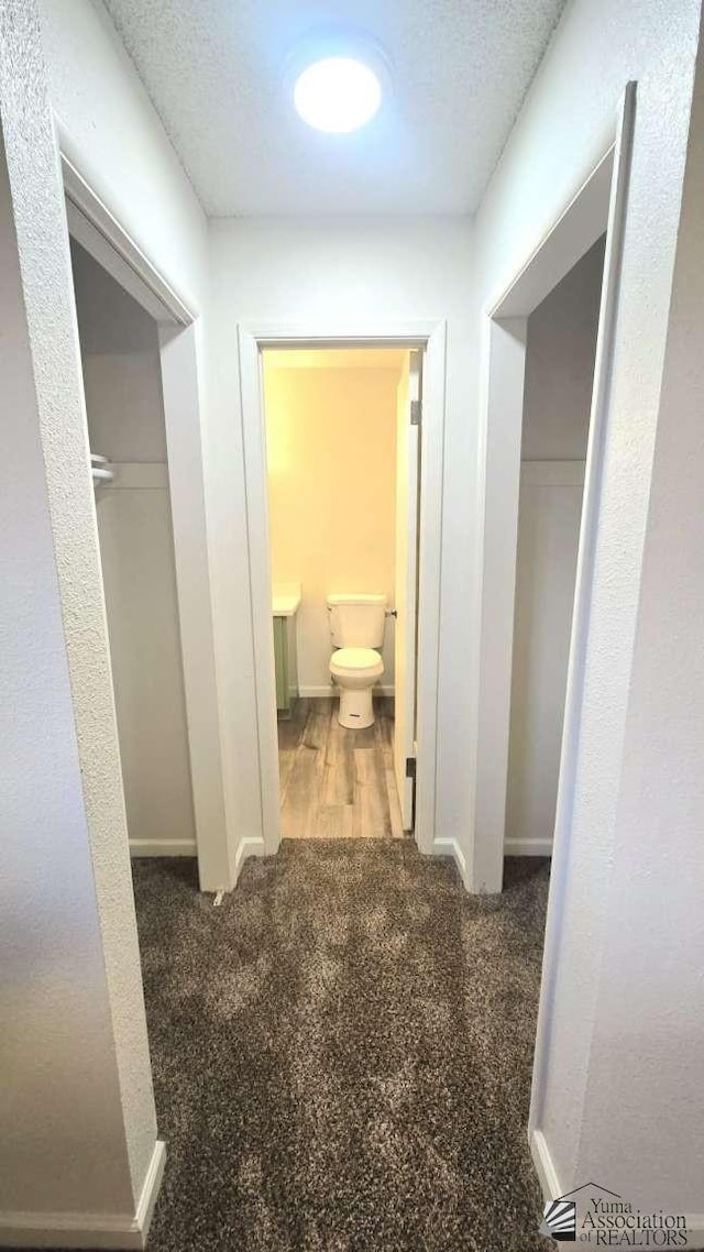 hall featuring baseboards and carpet flooring