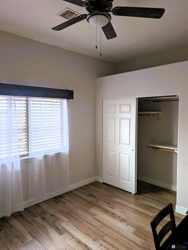 unfurnished bedroom featuring visible vents, a closet, baseboards, a ceiling fan, and light wood finished floors