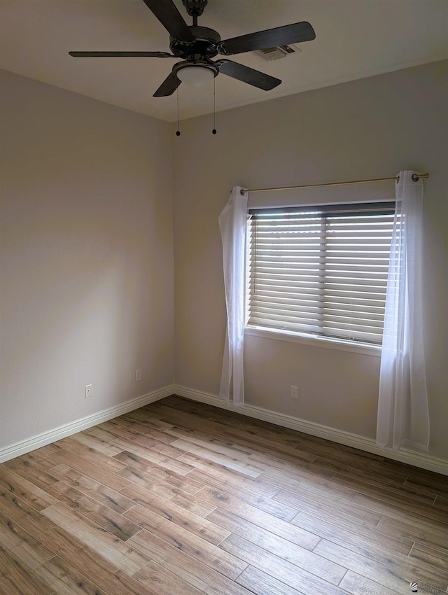 empty room featuring baseboards, ceiling fan, wood finished floors, and visible vents