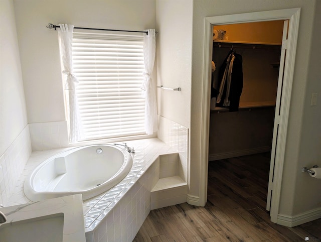 full bathroom featuring a walk in closet, a wealth of natural light, and wood finished floors
