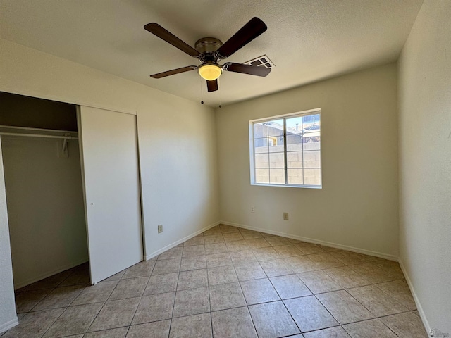 unfurnished bedroom with a ceiling fan, visible vents, light tile patterned floors, baseboards, and a closet
