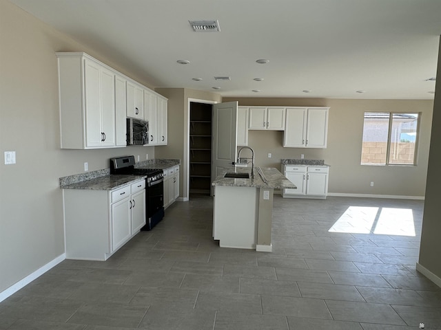 kitchen with black gas range, a kitchen island with sink, white cabinetry, and sink