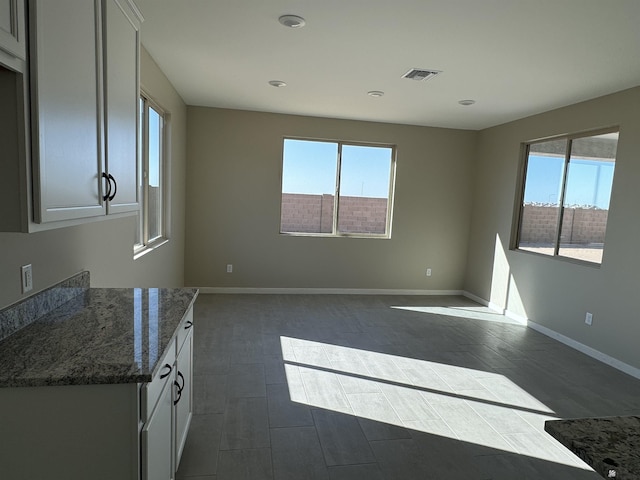 interior space featuring white cabinets and dark stone counters