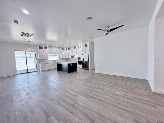 12360 E Calle Ln, Primera, Yuma, AZ 85367 - unfurnished living room with visible vents, baseboards, ceiling fan with notable chandelier, and light wood-type flooring