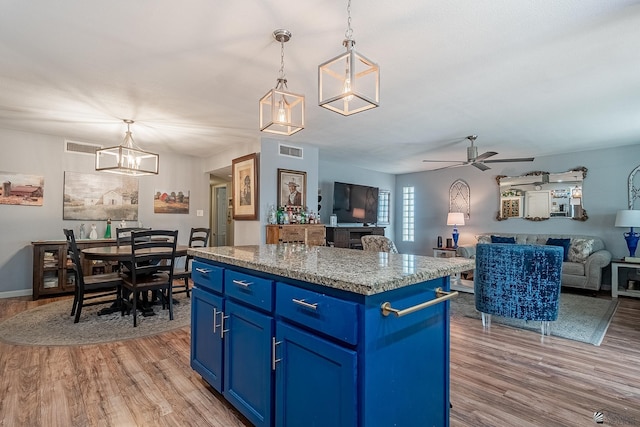 kitchen with a kitchen island, visible vents, light wood-style flooring, and blue cabinets