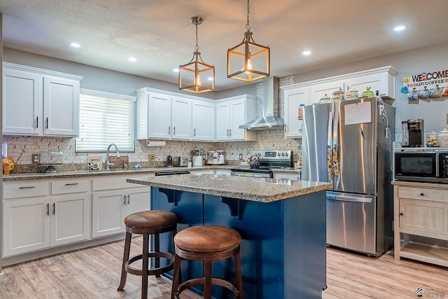 1302 W 17th St, Yuma, AZ 85364 - kitchen featuring a kitchen island, tasteful backsplash, wall chimney exhaust hood, stainless steel appliances, and light wood-style flooring