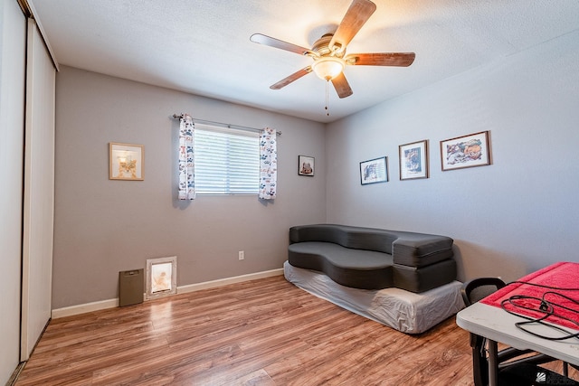 sitting room featuring baseboards, ceiling fan, and light wood-type flooring