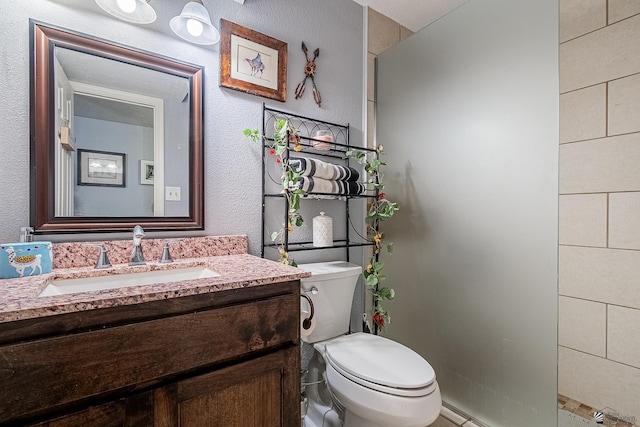 bathroom featuring vanity, walk in shower, and toilet