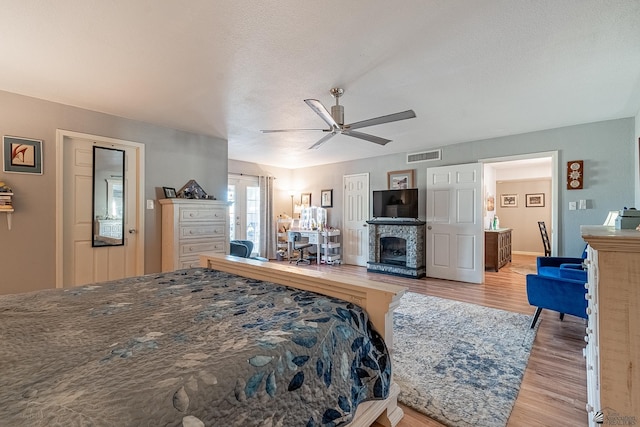 bedroom featuring ceiling fan, visible vents, wood finished floors, and a fireplace