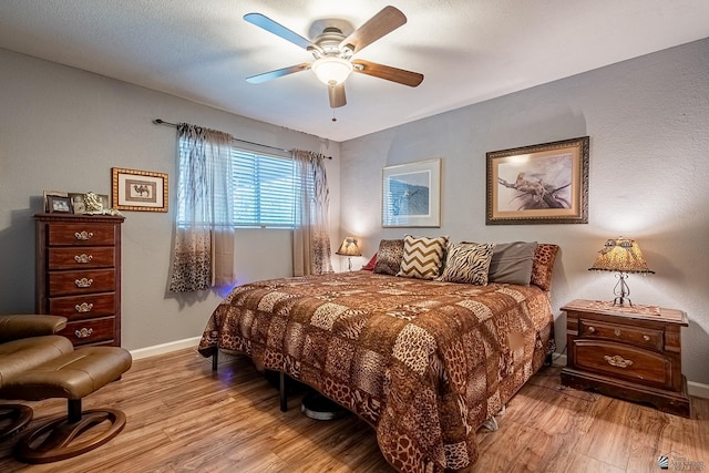 bedroom with light wood-style floors, baseboards, and ceiling fan