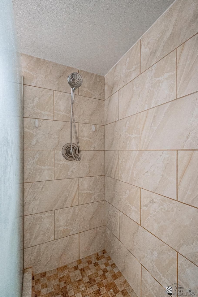 full bath featuring a textured ceiling and tiled shower