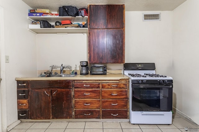 1127 S 13th Ave, Yuma, AZ 85364 - kitchen featuring gas range oven, light tile patterned floors, light countertops, and open shelves