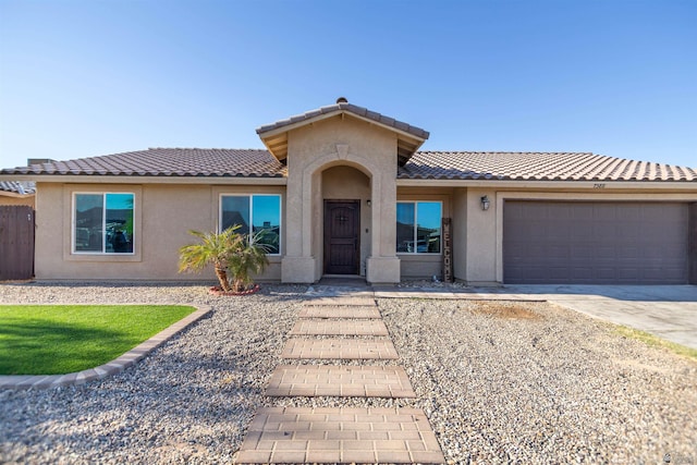 view of front facade with a tile roof, stucco siding, a garage, and driveway