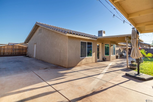 back of property with stucco siding, fence, a patio area, and a tiled roof