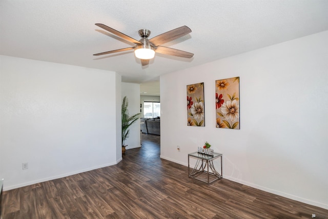 unfurnished room featuring ceiling fan, dark wood finished floors, and baseboards