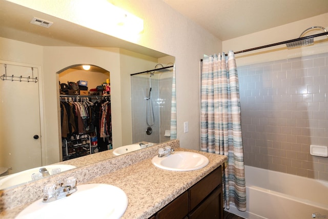 full bathroom featuring shower / tub combo with curtain, double vanity, and a spacious closet