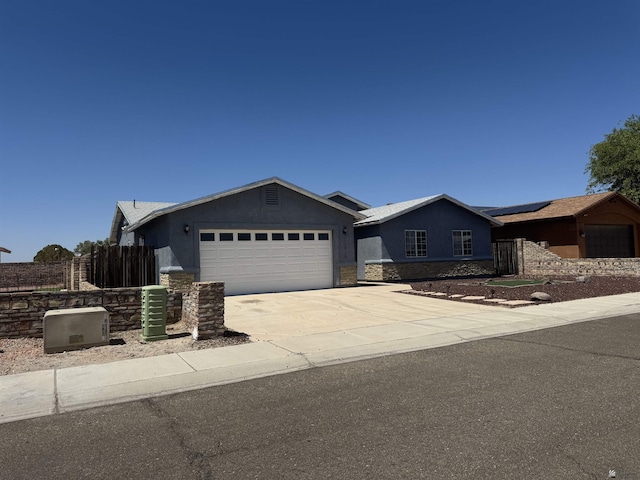 10310 E 37th Pl, Yuma, AZ 85365 - ranch-style home featuring a garage, stucco siding, stone siding, roof mounted solar panels, and driveway