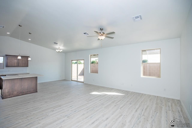 unfurnished living room featuring visible vents, vaulted ceiling, baseboards, ceiling fan with notable chandelier, and light wood-style flooring