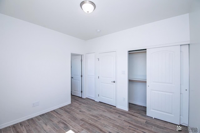 unfurnished bedroom featuring baseboards, a closet, and wood finished floors