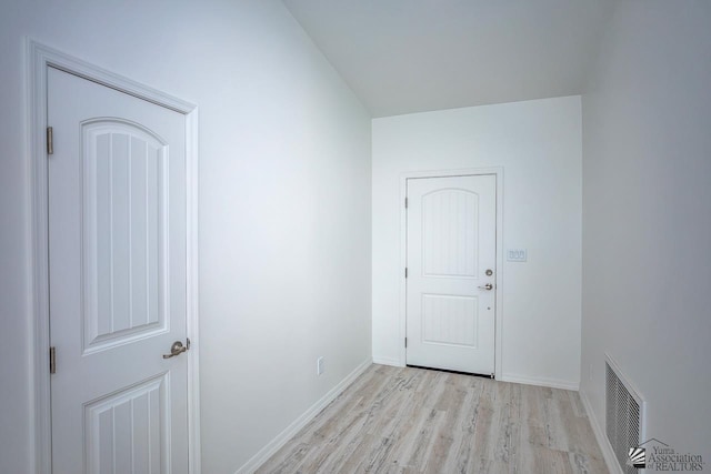 interior space with baseboards, light wood finished floors, and visible vents