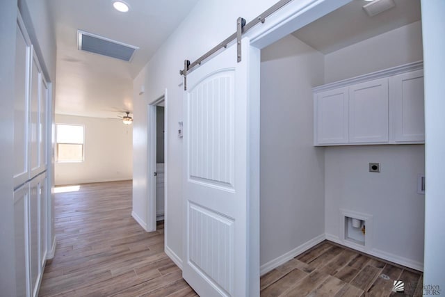 laundry area with a barn door, light wood-type flooring, electric dryer hookup, and cabinet space