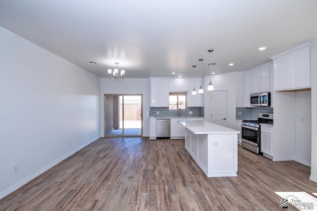 kitchen with a sink, light countertops, a chandelier, stainless steel appliances, and wood finished floors